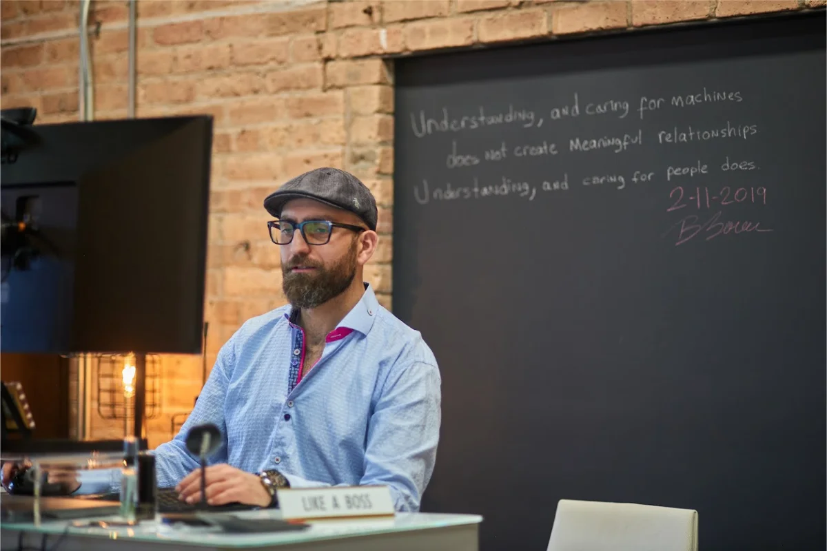Burak working at his desk, company quote and motive on white board behind him